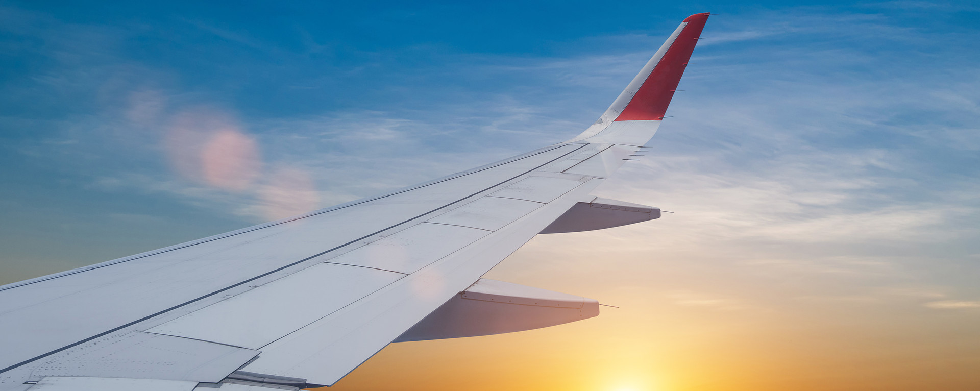 Airplane wing over a sunrise sky