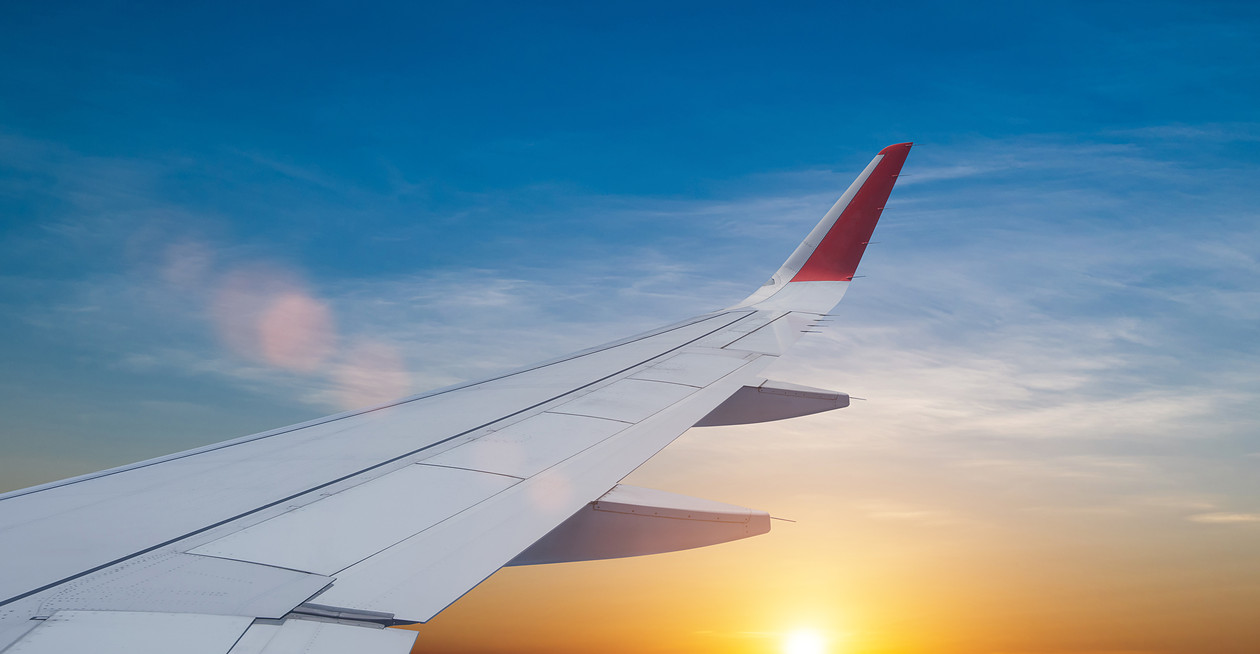 Airplane wing over sunrise sky